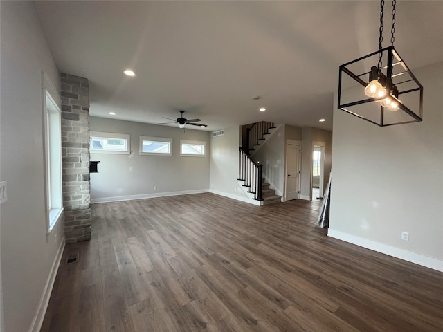 unfurnished living room featuring dark wood-type flooring and ceiling fan with notable chandelier