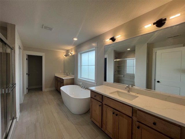 bathroom with vanity, plus walk in shower, hardwood / wood-style floors, and a textured ceiling