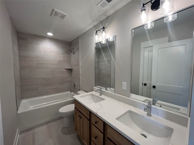 full bathroom with tiled shower / bath combo, vanity, a textured ceiling, and toilet