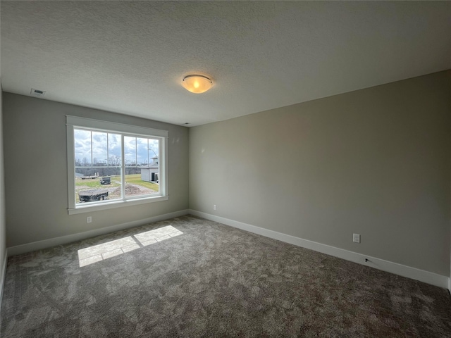 carpeted empty room featuring a textured ceiling