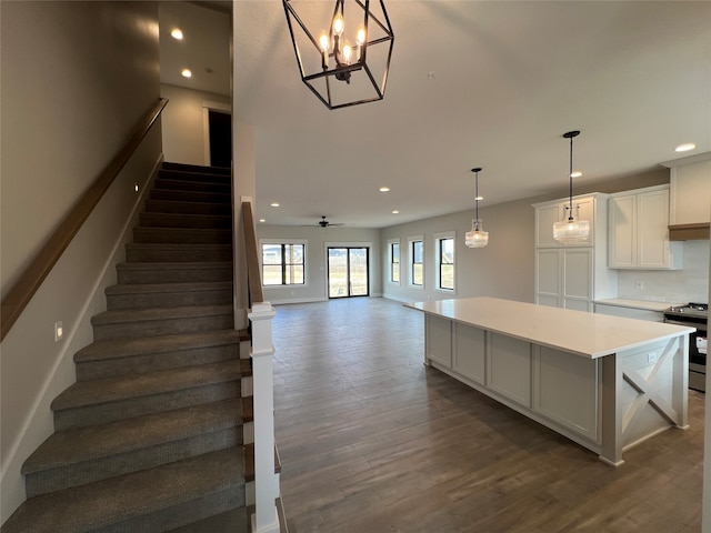 kitchen featuring stainless steel range with electric stovetop, a kitchen island, dark hardwood / wood-style flooring, hanging light fixtures, and white cabinets