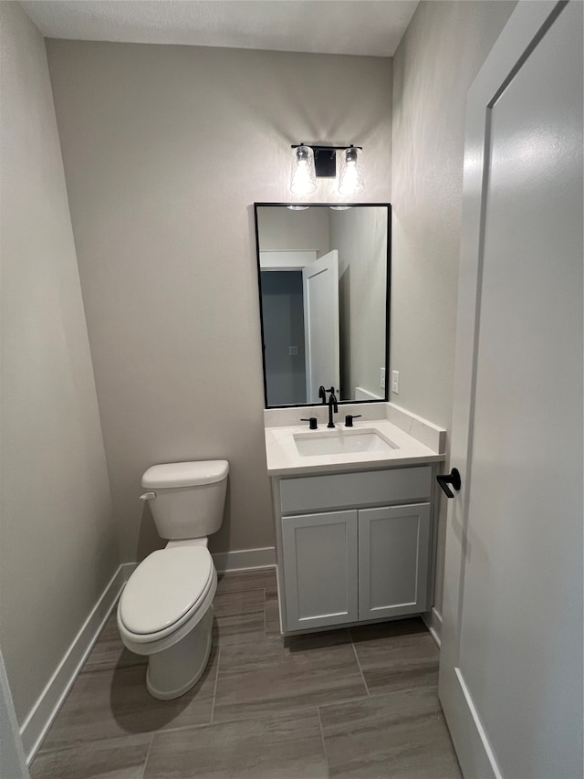 bathroom with hardwood / wood-style floors, vanity, and toilet