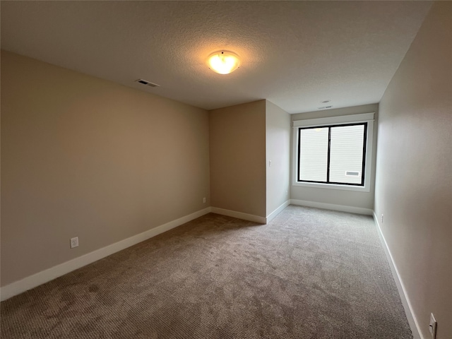 carpeted empty room featuring a textured ceiling