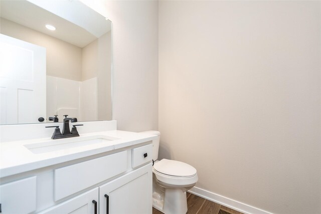 bathroom featuring vanity, toilet, walk in shower, and wood-type flooring