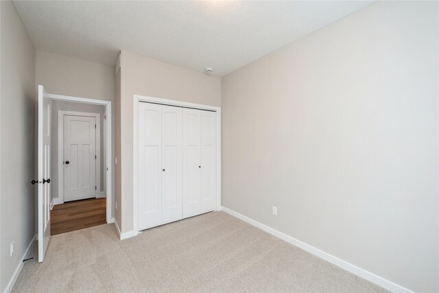 unfurnished bedroom featuring a closet and light carpet