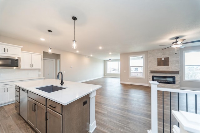 kitchen with sink, white cabinetry, a kitchen island with sink, and appliances with stainless steel finishes