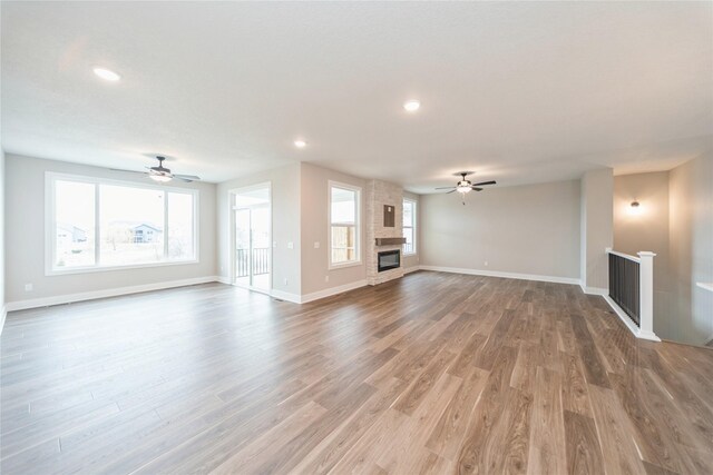 unfurnished living room featuring ceiling fan, hardwood / wood-style floors, and a fireplace