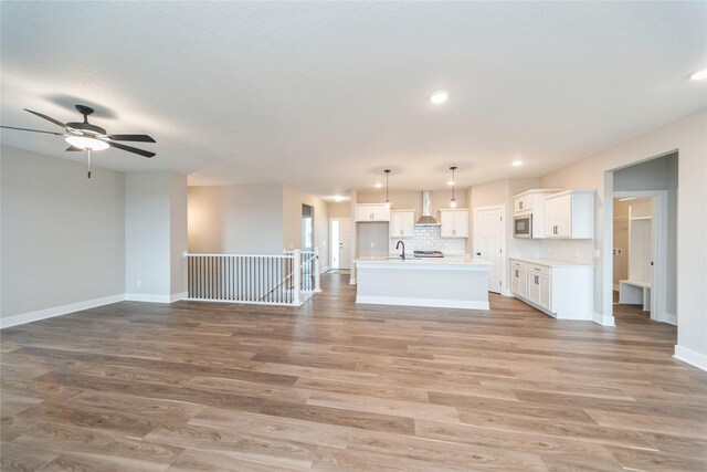 unfurnished living room featuring sink, ceiling fan, and light hardwood / wood-style floors