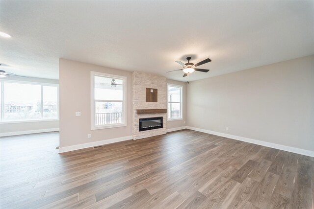 unfurnished living room with a fireplace, hardwood / wood-style flooring, and ceiling fan