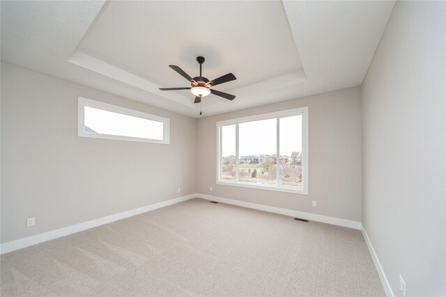 carpeted spare room featuring ceiling fan and a tray ceiling