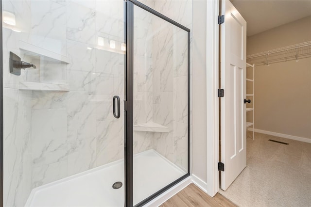 bathroom with a shower with shower door and hardwood / wood-style flooring