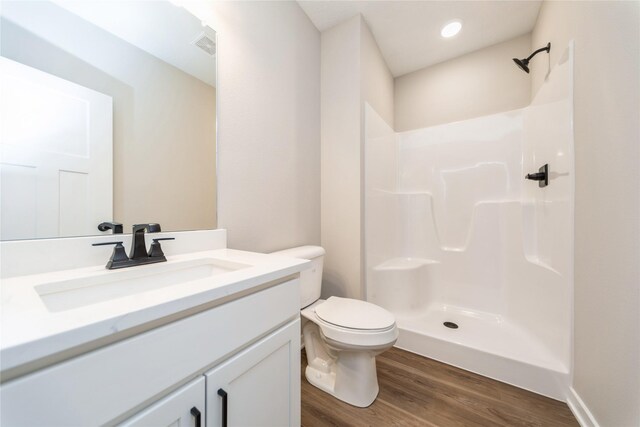 bathroom with wood-type flooring, toilet, vanity, and a shower