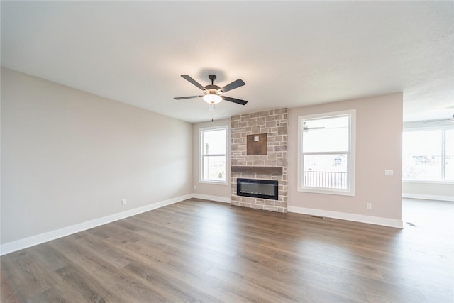 unfurnished living room with ceiling fan, dark wood-type flooring, heating unit, and a fireplace