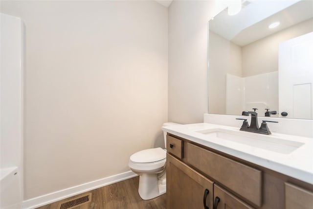 bathroom with hardwood / wood-style flooring, toilet, vanity, and walk in shower