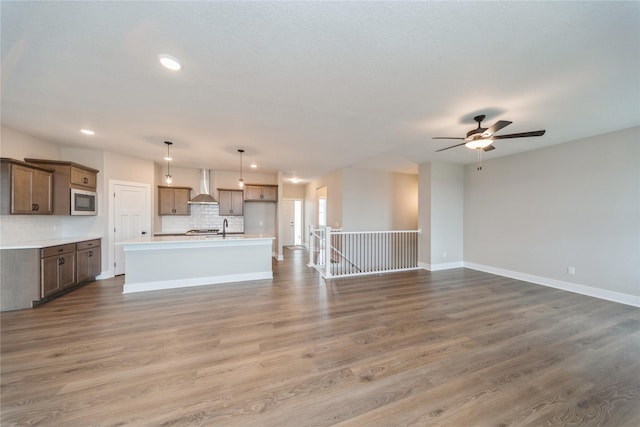 unfurnished living room with sink, hardwood / wood-style flooring, and ceiling fan