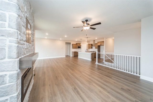 unfurnished living room featuring ceiling fan, sink, and hardwood / wood-style floors