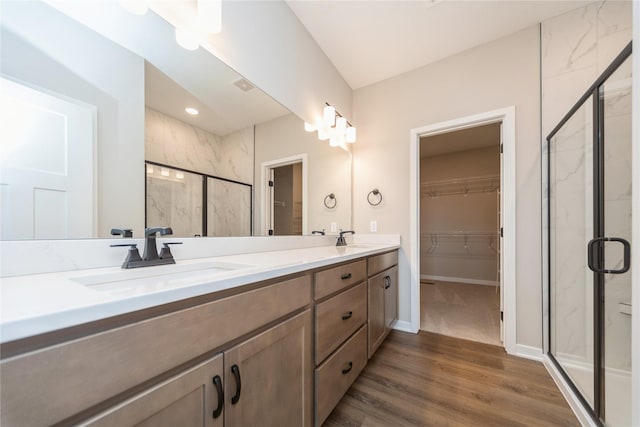 bathroom featuring wood-type flooring, a shower with door, and vanity