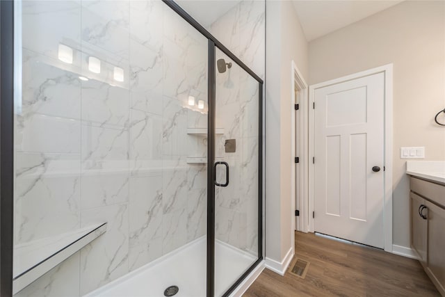 bathroom with hardwood / wood-style floors, a shower with door, and vanity