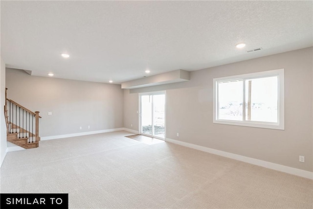 unfurnished room featuring light colored carpet, a healthy amount of sunlight, and a textured ceiling