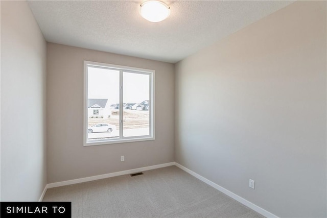 unfurnished room with carpet and a textured ceiling