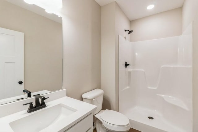 bathroom with walk in shower, vanity, and toilet