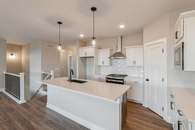 kitchen featuring a kitchen island with sink, dark wood-type flooring, sink, wall chimney range hood, and white cabinets