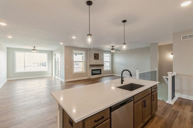 kitchen featuring pendant lighting, hardwood / wood-style flooring, stainless steel dishwasher, and sink