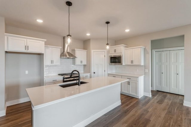 kitchen with white cabinetry, a kitchen island with sink, and wall chimney range hood