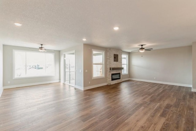 unfurnished living room featuring a wealth of natural light, a large fireplace, and dark wood-type flooring