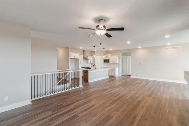 unfurnished living room featuring ceiling fan, dark hardwood / wood-style flooring, and sink