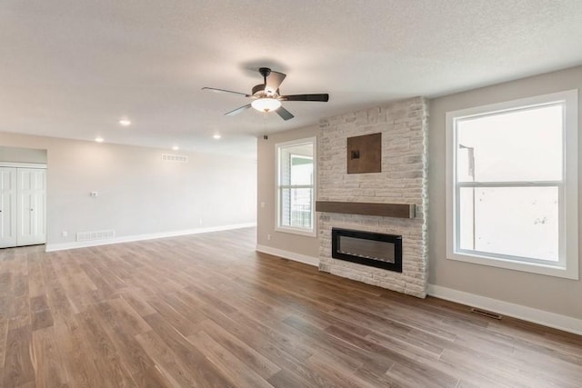 5608 NE Crk Ridge Dr, Ankeny, IA 50021 - unfurnished living room featuring a ceiling fan, a stone fireplace, wood finished floors, a textured ceiling, and recessed lighting