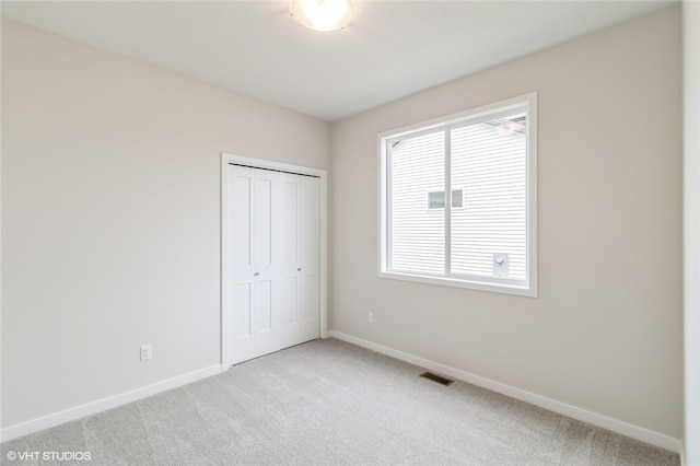 unfurnished bedroom featuring light carpet, multiple windows, and a closet