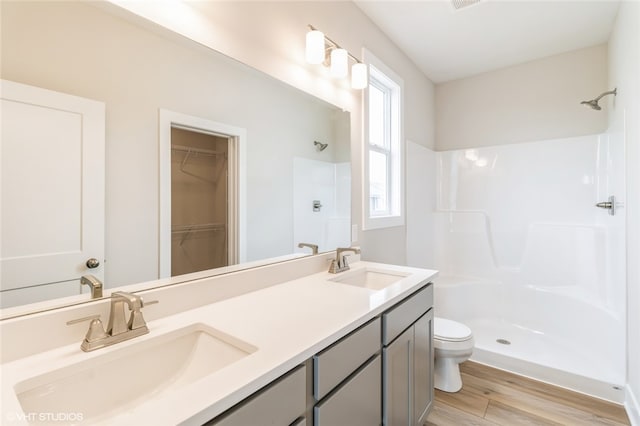 bathroom featuring toilet, walk in shower, vanity, and wood-type flooring