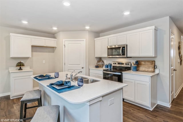 kitchen featuring an island with sink, stainless steel appliances, white cabinets, and dark hardwood / wood-style flooring