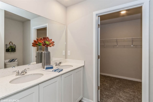 bathroom featuring toilet, large vanity, and double sink