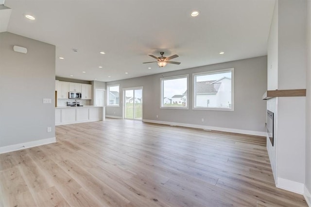 unfurnished living room featuring ceiling fan and light hardwood / wood-style floors