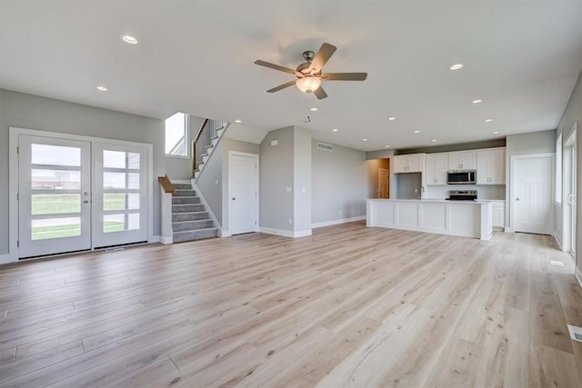 unfurnished living room featuring ceiling fan, light hardwood / wood-style flooring, and french doors