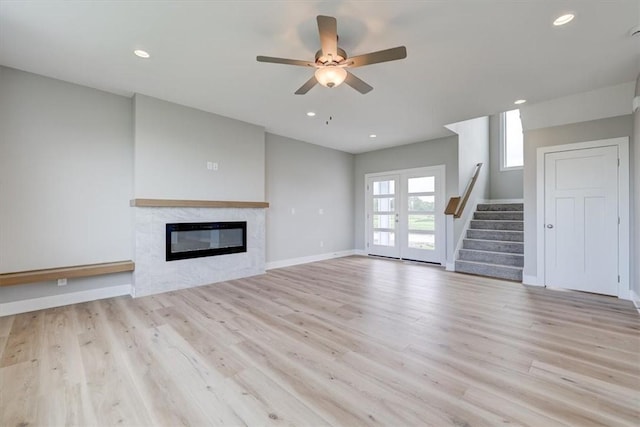 unfurnished living room featuring ceiling fan, light hardwood / wood-style floors, and a tile fireplace