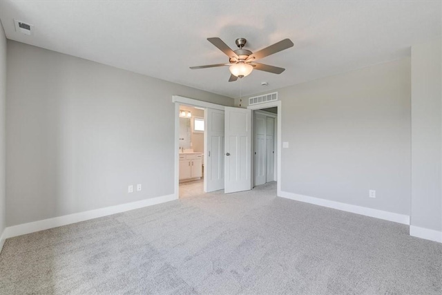 unfurnished bedroom featuring ensuite bath, ceiling fan, and light colored carpet