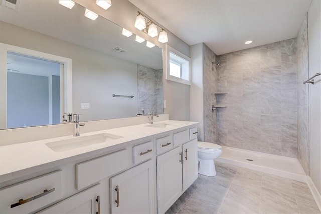 bathroom with a tile shower, tile patterned floors, vanity, and toilet