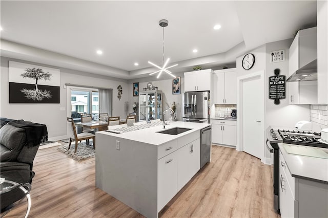 kitchen with light hardwood / wood-style floors, stainless steel appliances, white cabinets, backsplash, and sink