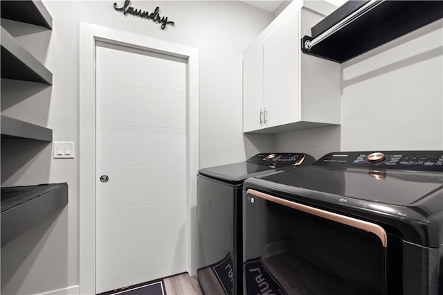 clothes washing area with hardwood / wood-style floors, washer and clothes dryer, and cabinets