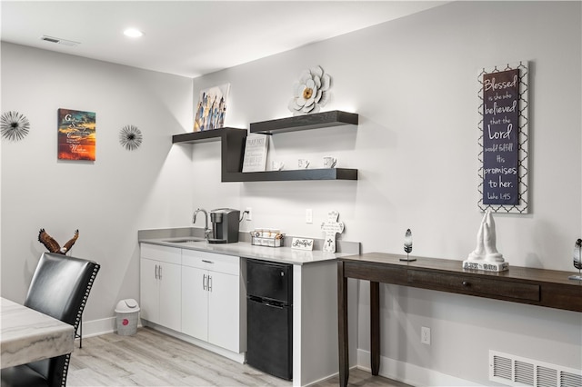 bar with white cabinets, light hardwood / wood-style flooring, and sink