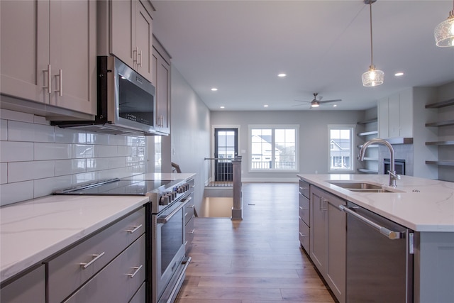 kitchen with hanging light fixtures, appliances with stainless steel finishes, gray cabinetry, light hardwood / wood-style floors, and sink