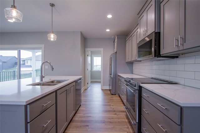 kitchen featuring appliances with stainless steel finishes, a healthy amount of sunlight, sink, and light hardwood / wood-style floors