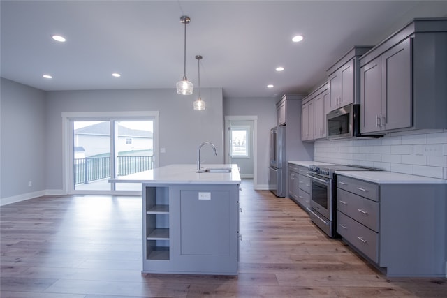 kitchen featuring stainless steel appliances, a wealth of natural light, light wood-type flooring, and hanging light fixtures