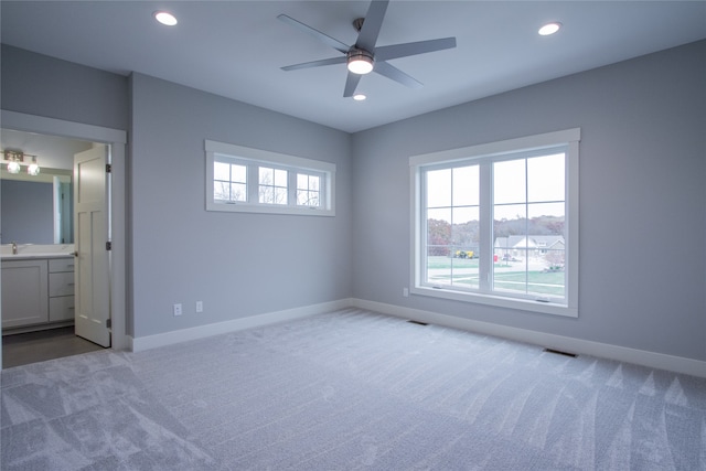 unfurnished bedroom with light carpet, ensuite bathroom, and ceiling fan