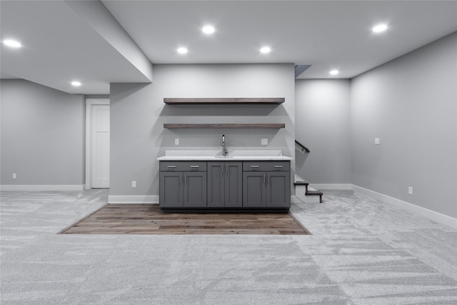 bar with sink, light carpet, and gray cabinetry