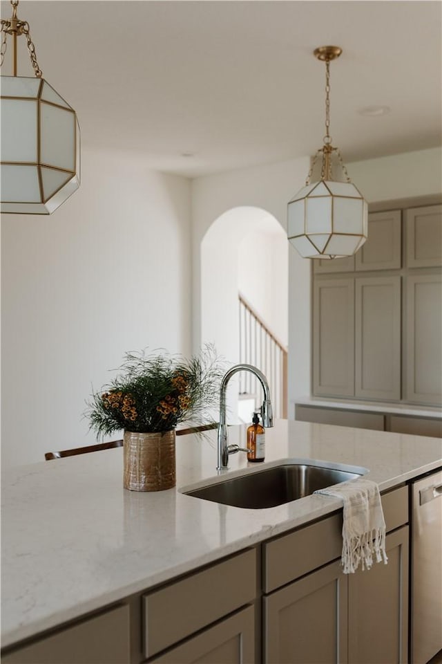 kitchen with light stone counters, sink, stainless steel dishwasher, and gray cabinetry