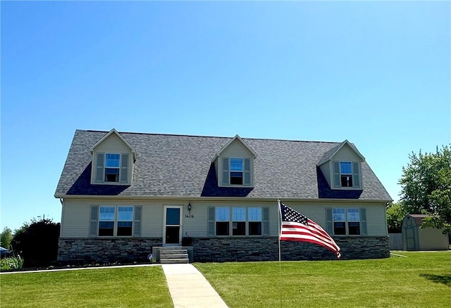 cape cod home with a storage unit and a front yard